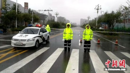 低洼路段严重积水，为防车辆遇险，沛县交警冒雨守候路口警戒线外。