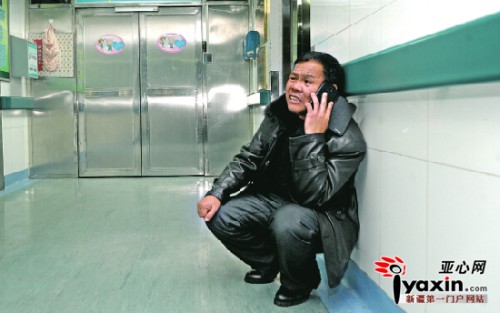 1月11日晚，在自治区人民医院重症医学二科的楼道里，疲惫的秦正君蹲靠在墙边四处打电话借钱。亚心网记者 张万德 摄